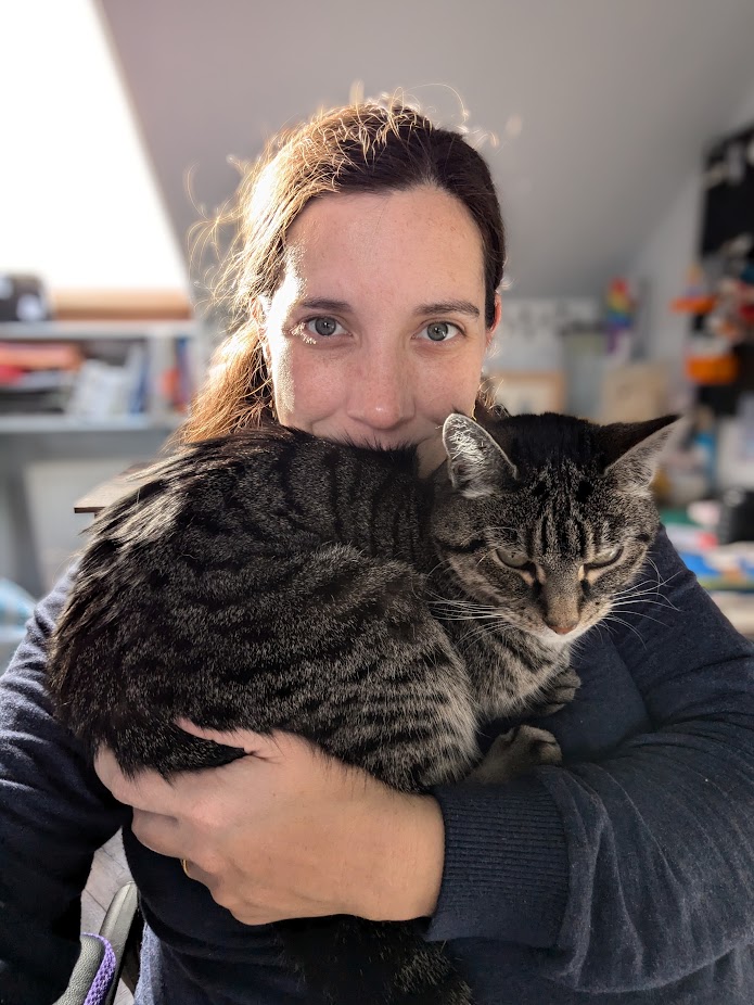 A selfie of me, a late thirties woman and a silver tabby cat sitting on my chest.